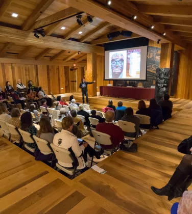 People sitting in a large room looking at a screen